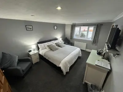a bedroom with a bed and a chair and a television at Southpark House in Dumfries
