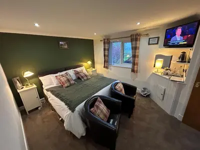 a bedroom with a large bed and a flat screen tv at Southpark House in Dumfries