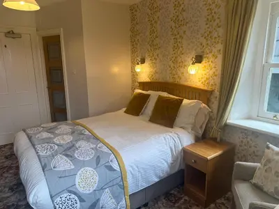 a bedroom with a bed and a chair and a window at Burleigh Mead in Keswick