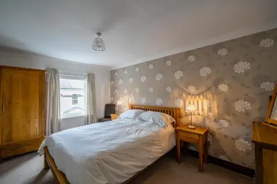 a bedroom with a bed and a night stand with a lamp at Acorn Apartment 2 (upper) in Keswick