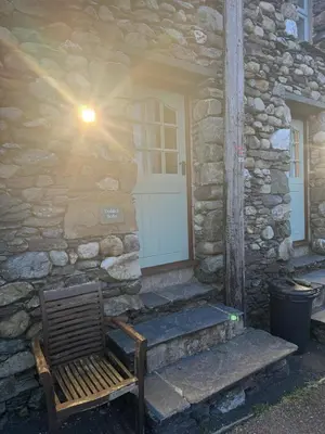 a bench sitting outside of a stone house with a door at Doddick Bothy in Threlkeld