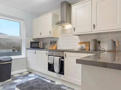 a kitchen with white cabinets and a stove top oven at Miterdale A Wonderful Home in the Idyllic Duddon Valley in Broughton in Furness