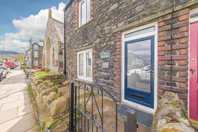 a brick building with a blue door on a street at Blue Sky Cottage in Keswick