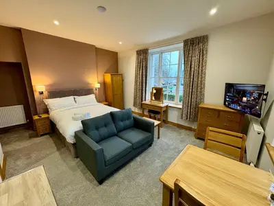 a hotel room with a bed and a couch and a tv at Grindal Studio Apartments - Newly Opened Luxury Accommodation in St Bees