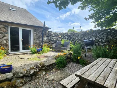 a garden with a stone wall and a wooden bench at 1 Bed in Eskdale 94530 in Eskdale