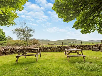 two picnic tables in a field with a stone wall at 1 Bed in Eskdale 94530 in Eskdale