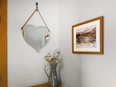 a mirror on a wall next to a vase with flowers at Pippa's Cottage - Uk42332 in Little Blencow