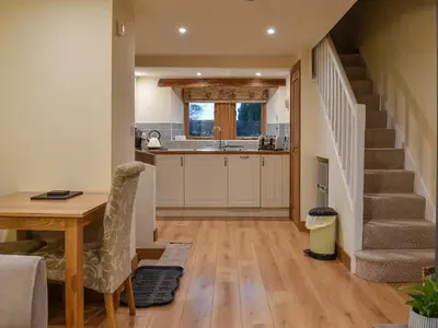 a kitchen and dining room with a table and a staircase at Pippa's Cottage - Uk42332 in Little Blencow