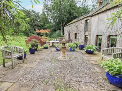 a garden with benches and potted plants and a building at The Gardener's Bothy in Penrith