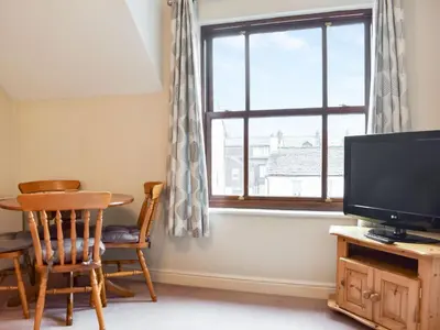 a living room with a television and a table and a window at Grisedale View - Hewetson Court in Keswick