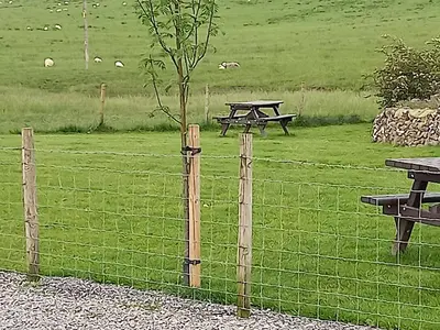 a fence with a picnic table in a field at Green Dream in Cockermouth