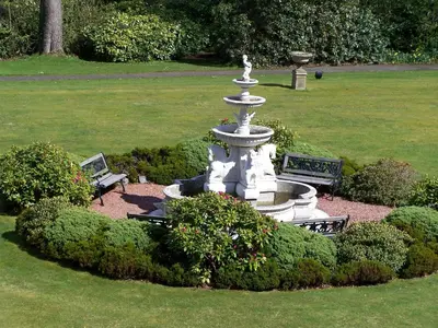 a fountain in the middle of a garden with bushes at The Ennerdale Country House Hotel ‘A Bespoke Hotel’ in Cleator