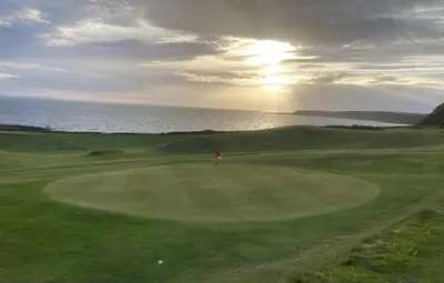 a view of a golf course with the ocean in the background at Beautifully Presented 2 Bedroom Static Caravan in Monreith