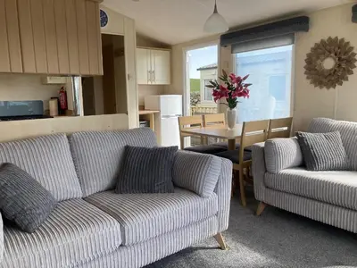 a living room with two couches and a table at Beautifully Presented 2 Bedroom Static Caravan in Monreith