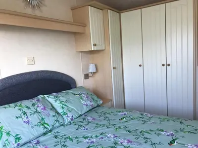 a bedroom with a bed with a green comforter at Beautifully Presented 2 Bedroom Static Caravan in Monreith
