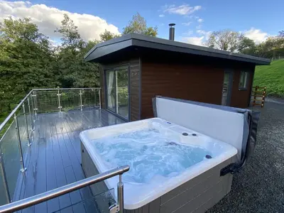 a hot tub on the deck of a house at Laigh Letterpin Lodge in Girvan