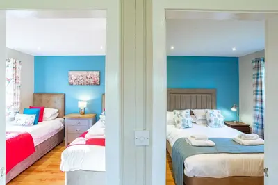 two beds in a room with blue walls at Birch Lodge in Newton Stewart