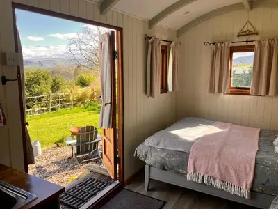 a small bedroom with a bed and a window at Archie the shepherd’s hut in Penruddock