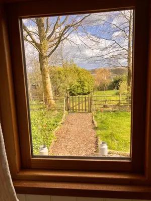 a window with a view of a gate and a field at Archie the shepherd’s hut in Penruddock
