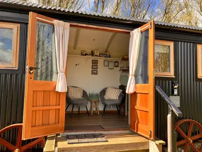 an open door of a tiny house with a deck at Archie the shepherd’s hut in Penruddock