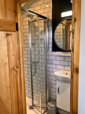 a bathroom with a shower and a sink at Archie the shepherd’s hut in Penruddock