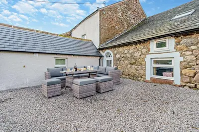 a patio with chairs and a table in front of a building at 4 Bed in Kinniside oc-c28854 in Frizington