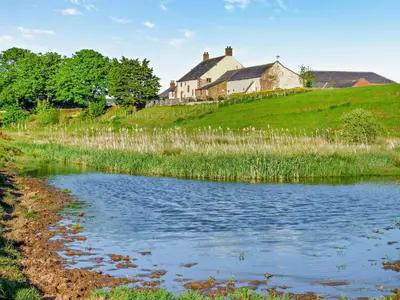 a house on top of a hill next to a pond at 2 Bed in Irthington oc-m28305 in Irthington