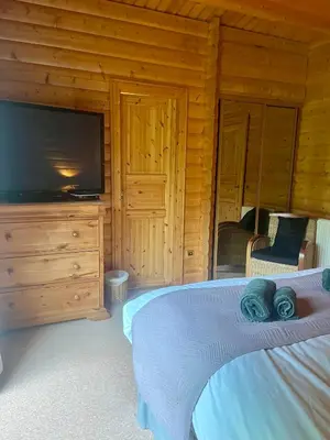 a bedroom with a bed and a flat screen tv at Kipplochan in Dalbeattie