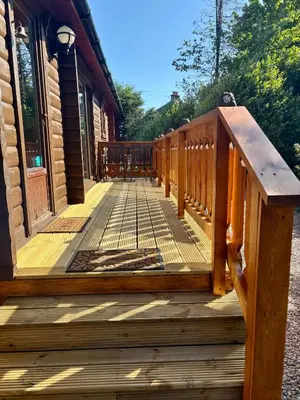 a wooden porch of a cabin with a wooden railing at Kipplochan in Dalbeattie