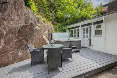 a wooden deck with a table and chairs and a tub at Rockwood- Grasmere family cottage with Hot tub in Grasmere