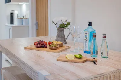 a table with two cutting boards with fruit and a bottle of alcohol at Rockwood- Grasmere family cottage with Hot tub in Grasmere