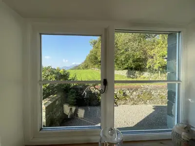 a window with a view of a field through it at Deer Close Cottage in Keswick