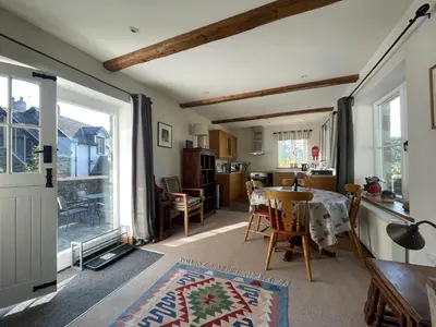 a living room with a table and a window at Deer Close Cottage in Keswick