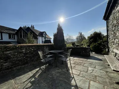 a patio with a table and chairs on a stone wall at Deer Close Cottage in Keswick