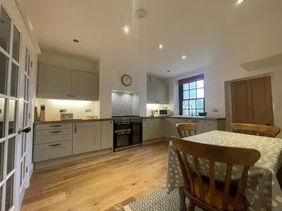 a kitchen with white cabinets and a table with chairs at Fell View in Portinscale