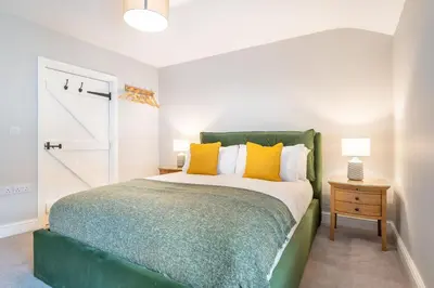 a bedroom with a green bed with yellow pillows at Little Ada in Keswick