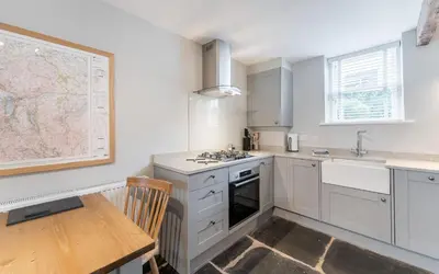 a white kitchen with a table and a map on the wall at Little Ada in Keswick