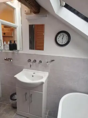 a bathroom with a sink and a clock on the wall at Tanners Cottage in Cockermouth