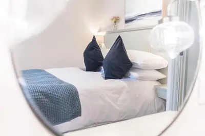 a mirror reflection of a bed with blue pillows at Otterbield, Derwent House, Portinscale in Portinscale