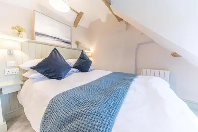 a bedroom with a large white bed with blue pillows at Otterbield, Derwent House, Portinscale in Portinscale