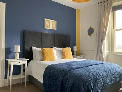 a bedroom with a large bed with yellow pillows at Laurel Bank House in Penrith