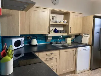 a kitchen with wooden cabinets and a sink and a refrigerator at Laurel Bank House in Penrith