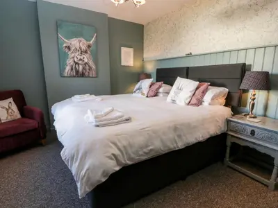 a bedroom with a bed with a picture of a cow on the wall at Smithy House in Dumfries