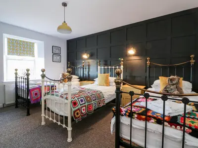 two twin beds in a bedroom with a black wall at Smithy House in Dumfries