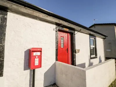 a red mail box on the side of a building with a red door at Smithy House in Dumfries