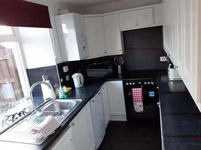 a kitchen with white cabinets and a sink and a stove at Odea Hot tub Holiday Cottage in Maxwelltown