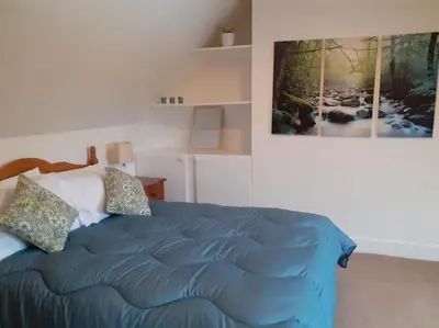 a bedroom with a blue bed with a picture on the wall at Odea Hot tub Holiday Cottage in Maxwelltown