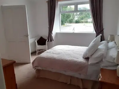 a bedroom with a large bed and a window at Odea Hot tub Holiday Cottage in Maxwelltown