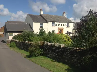 a hotel with a stone wall in front of a house at Wheyrigg Hall Hotel in Wheyrigg