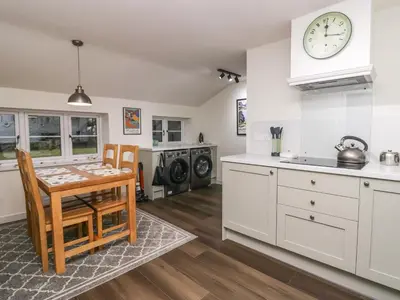 a kitchen with white cabinets and a table with chairs at The Barn in Seascale